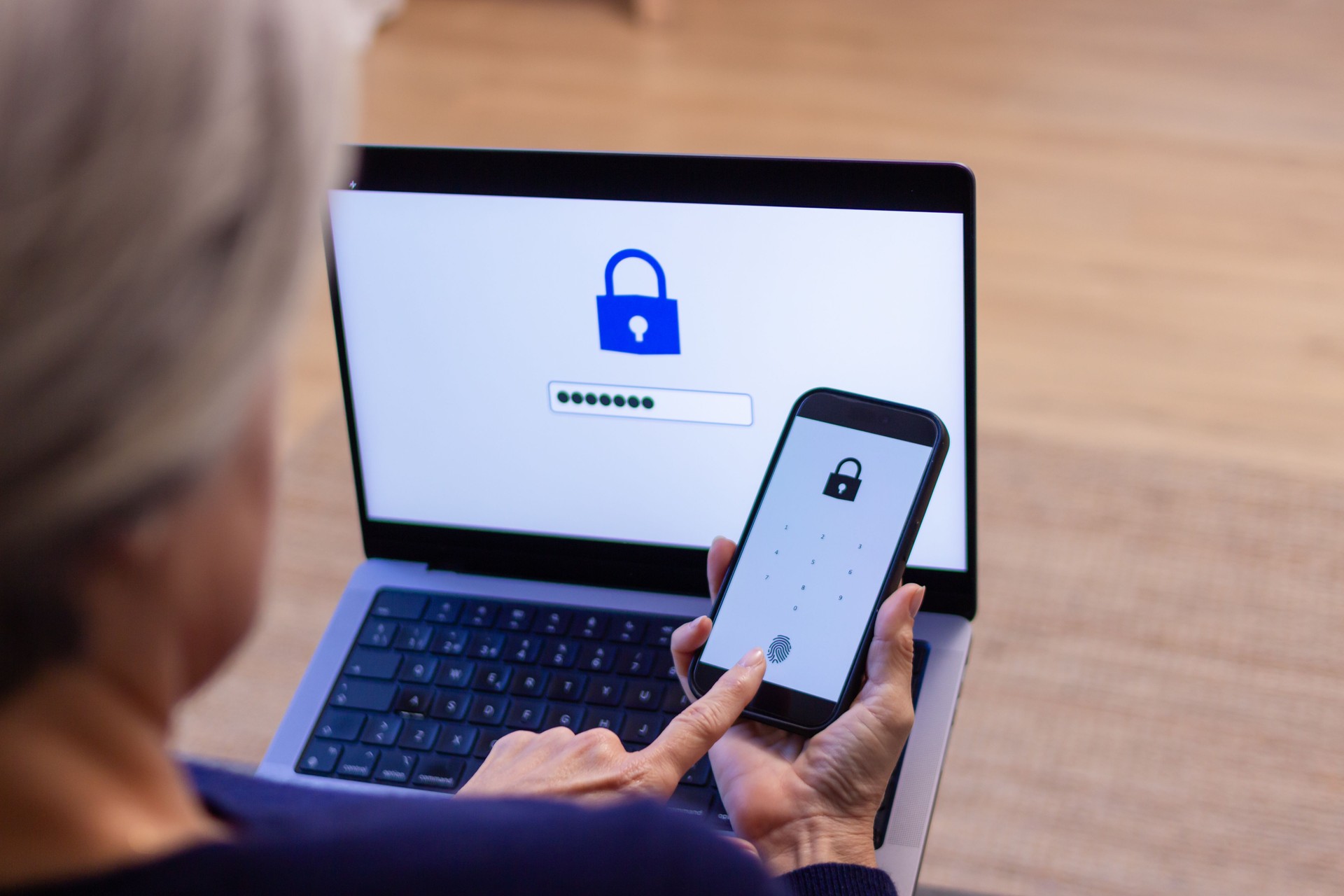 Senior woman using two-factor authentication on laptop and smartphone Senior woman using two-factor authentication on laptop and smartphone