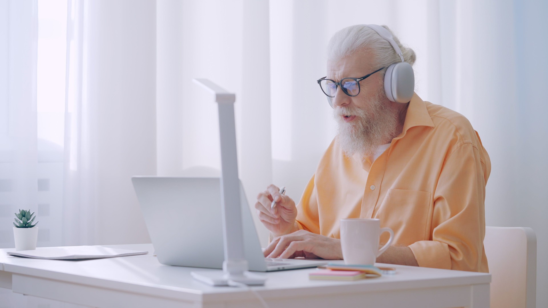 A man in his 60s works as an online tutor, having a video call and talking to coworkers A man in his 60s works as an online tutor, having a video call and talking to coworkers